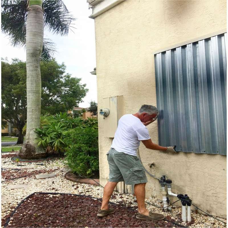 Image of man putting up hurricane shutters